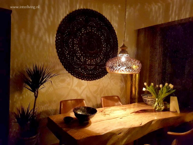 Binnenkijken rond oosters wandpaneel met filigrainlamp boven eettafel